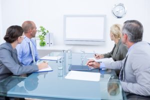 Collaborateurs réunis autour d'une table de conférence suivant une présentation sur écran lors des consultations obligatoires du CSE