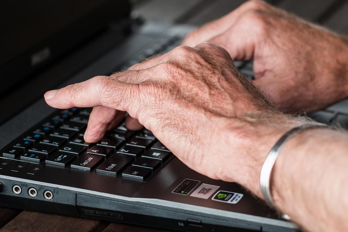Des mains ridées tapent sur le clavier d'un ordinateur portable Des mains ridées tapent sur le clavier d'un ordinateur portable