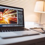 Un ordinateur portable sur un bureau, une lampe allumée, une photo en cours d'édition