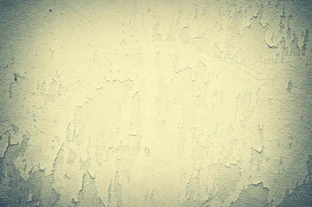 Mur recouvert d'enduit peint beige, très fissuré et écaillé par l'humidité